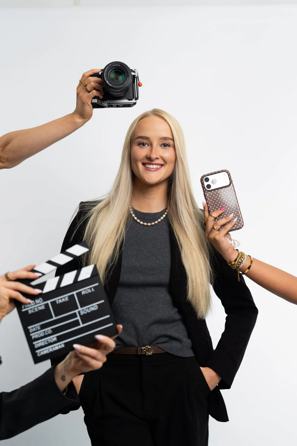 Account manager holding a clapperboard and a phone while a camera is pointed at her