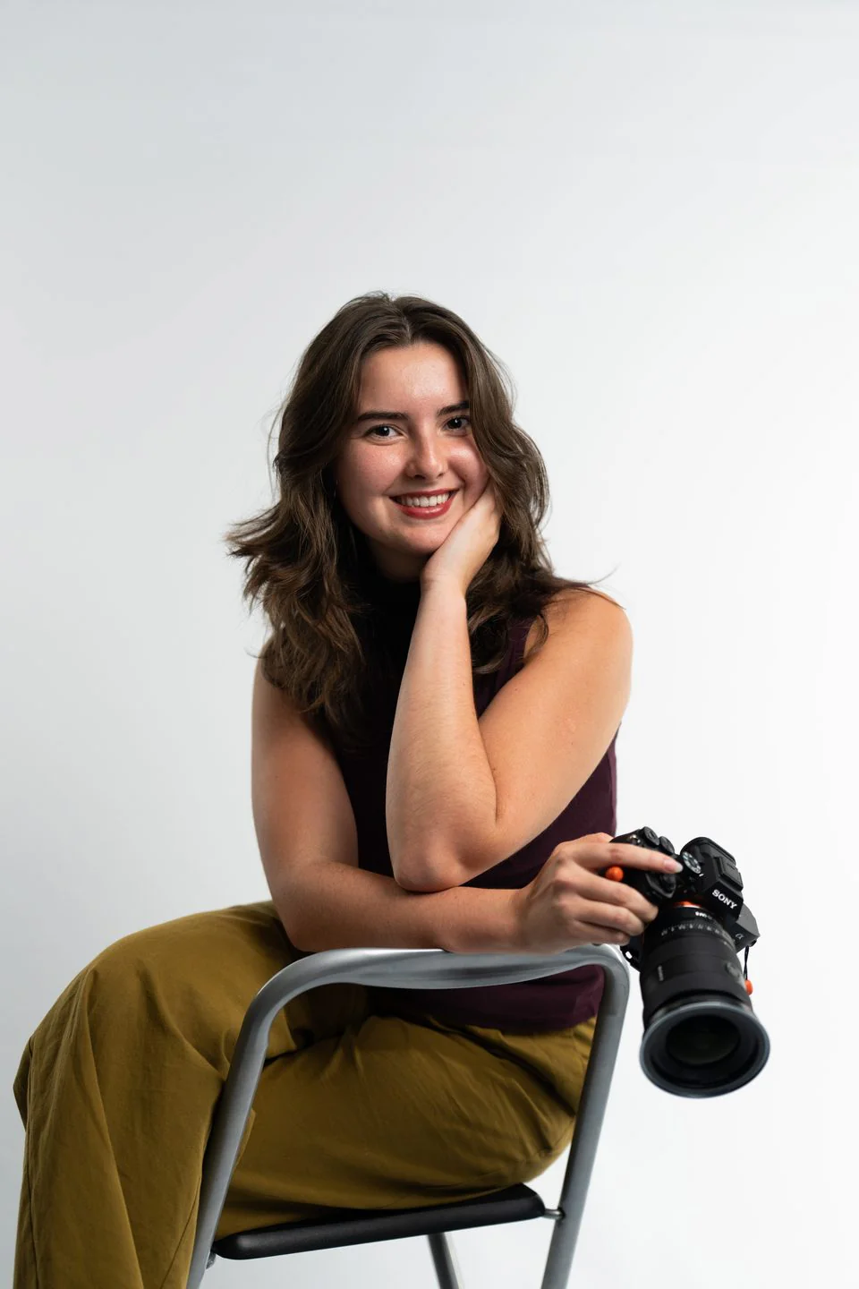 Videographer leaning on a studio chair with a camera in her hand