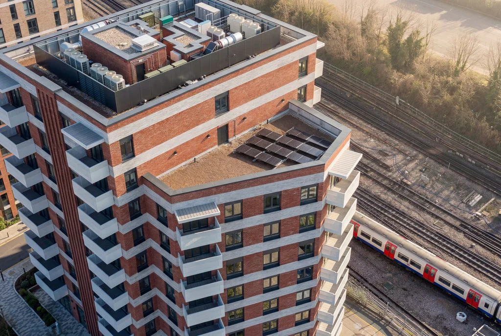 Aerial view of a red-brick apartment block beside railway tracks