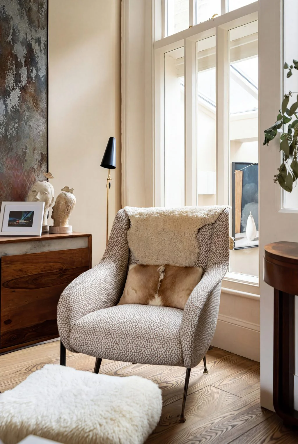 Armchair with sheepskin throw beside a tall sash window