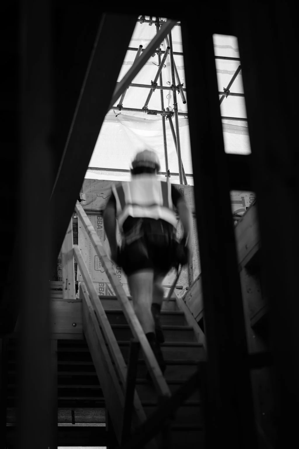 Construction worker climbing scaffold stairs, black and white