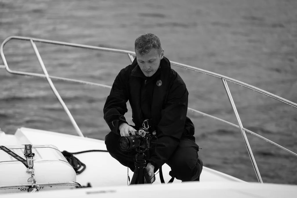Photographer crouched on a boat bow at sea