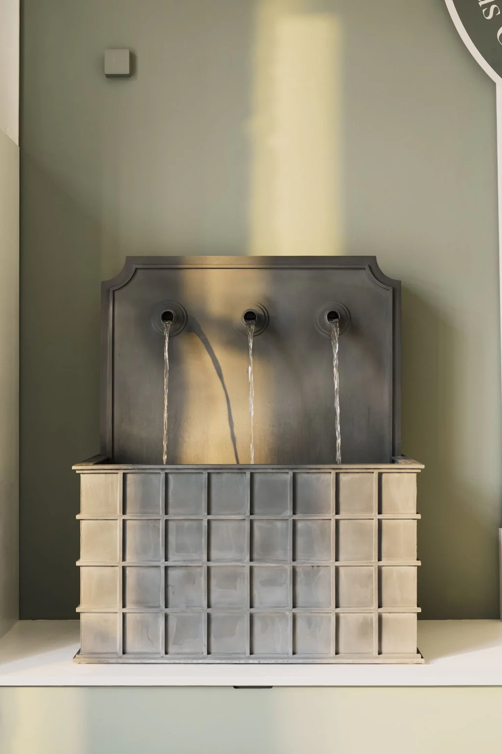 Steel garden water feature against a plain wall
