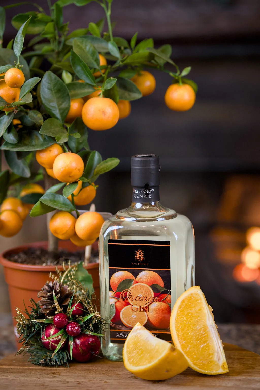 Bottle of orange gin with clementines beside a fire