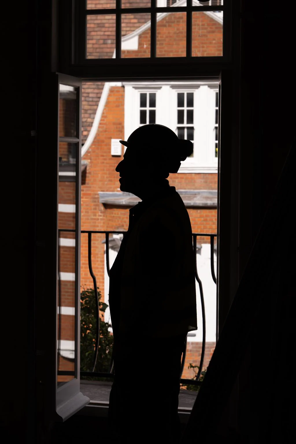 Silhouetted worker at a window above city rooftops