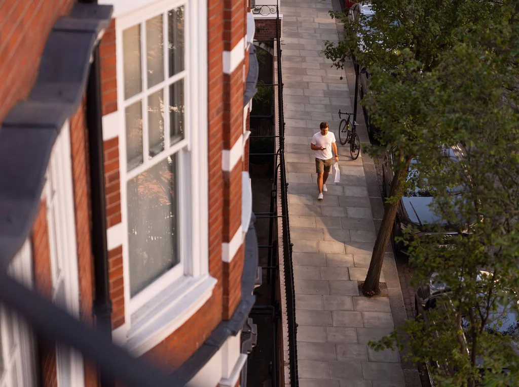 Pedestrian below a red-brick mansion block