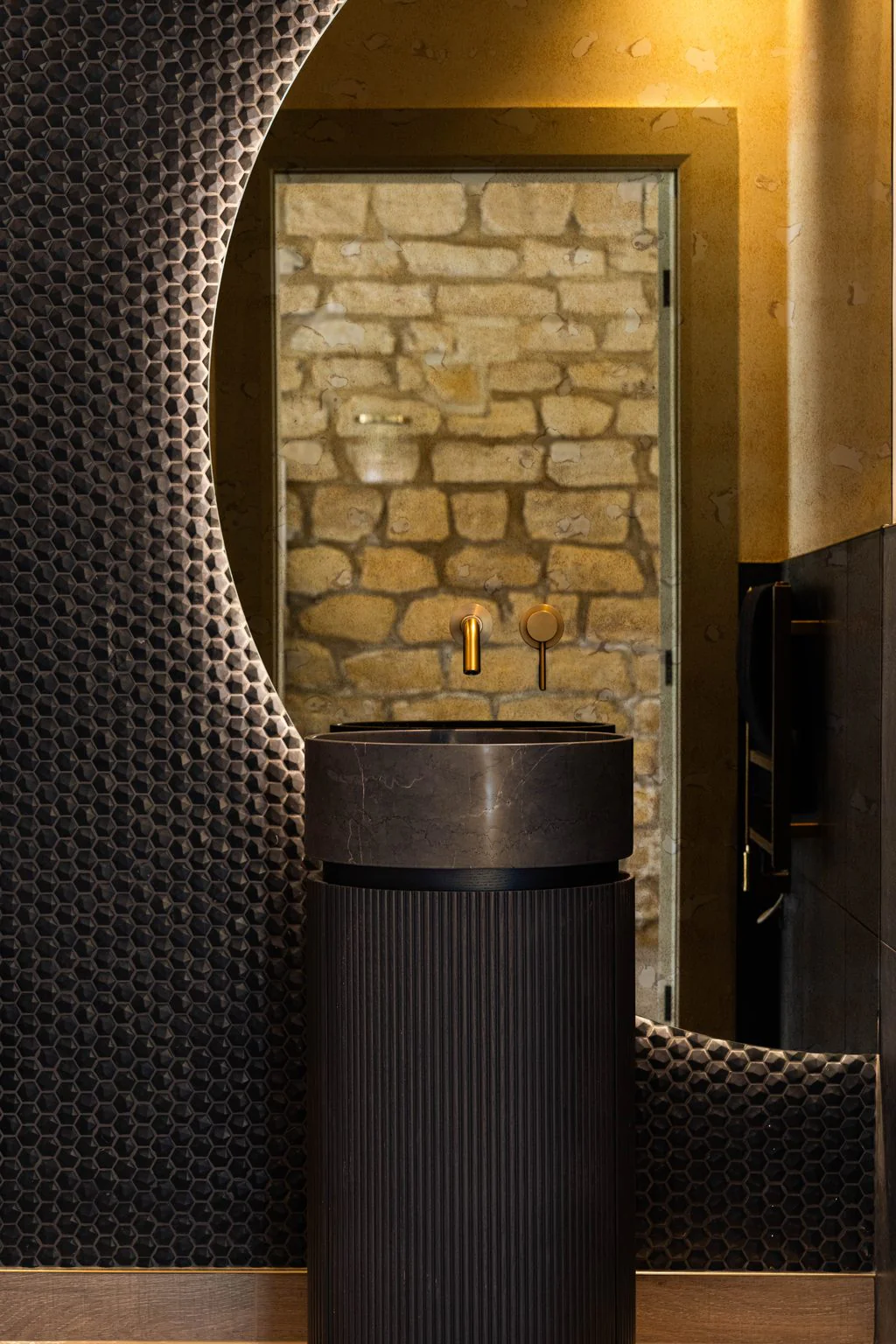 Black fluted basin against a textured stone wall
