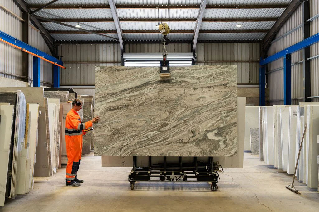 Worker moving a stone slab in a warehouse