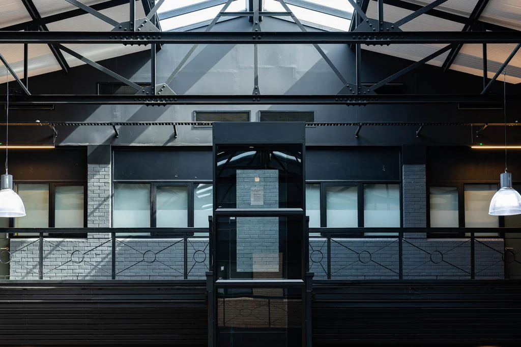 Dark-clad office facade under a glazed roof