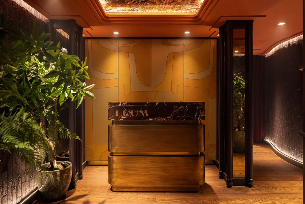 Reception desk in a dark timber and brass hotel lobby